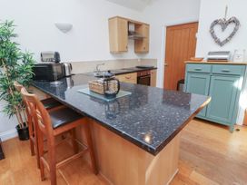 A kitchen with counter, stools, and appliances at Hideaway Cottage No 1 Seahouses
