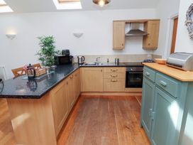 A kitchen with cabinets and appliances at Hideaway Cottage No 1 Seahouses