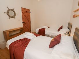 A bedroom with two beds and a wooden table at Hideaway Cottage No 1 in Seahouses