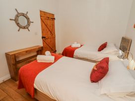 A bedroom with two beds and a wooden door at Hideaway Cottage No 1 in Seahouses