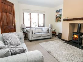 A living room with a sofa, table, lamp, and fireplace at Dolly Blue in Backbarrow near Newby Bridge