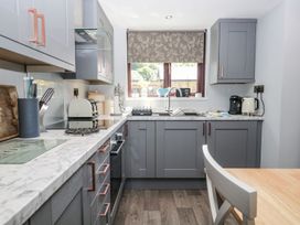 A kitchen with gray cabinets and appliances at Dolly Blue Backbarrow near Newby Bridge