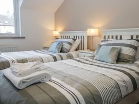 A bedroom with two beds and a bedside lamp at Dolly Blue in Backbarrow near Newby Bridge