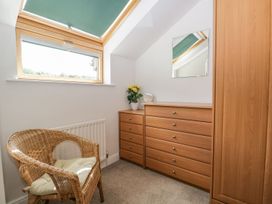 A bedroom with a dresser, chair, and window at Dolly Blue Backbarrow near Newby Bridge