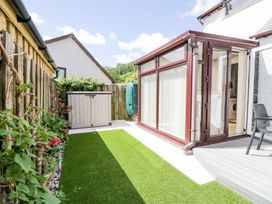 A garden with a storage box and a conservatory at Dolly Blue Backbarrow near Newby Bridge