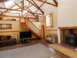 A living room with a television, stairs, and a fireplace at Millbarn in Crowcombe