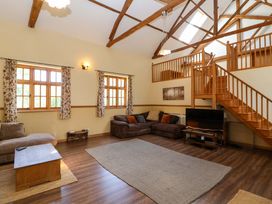 A living room with a sofa, coffee table, and television at Millbarn in Crowcombe