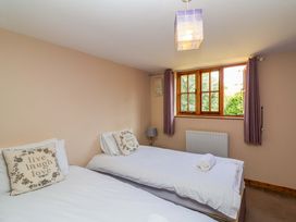 A bedroom with two beds and a window at Millbarn in Crowcombe