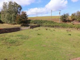 A garden with a gate and trees at Millbarn in Crowcombe