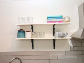 A shelf with glasses, cookbooks, a jar and mugs at 2 Sheplegh Court in Blackawton near Dartmouth