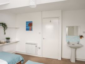 A bedroom with a bed, shelf, plant, radiator, door and sink at Fadrun - 3 Ty'n Don