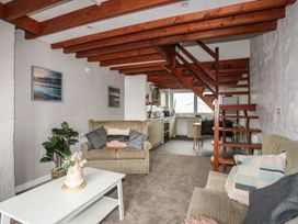 A living room with a sofa, table, and stairs leading to a kitchen at Penrhyn - 4 Ty'n Don