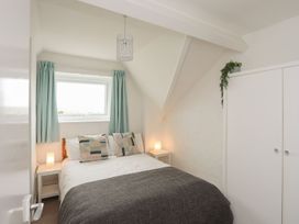 A bedroom with a bed, curtains, and a wardrobe at Penrhyn - 4 Ty'n Don