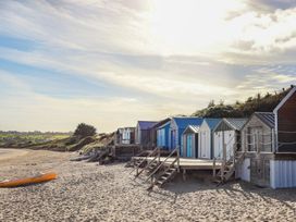 Beach huts on a sandy beach with a kayak at Penrhyn - 4 Ty'n Don