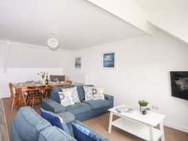 A living room with a sofa and dining table at Towyn - 7 Ty'n Don