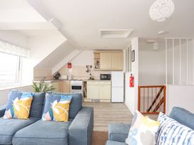 A living room with a kitchen area and sofa at Towyn - 7 Ty'n Don