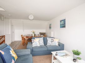 A living room with a sofa and dining area at Towyn - 7 Ty'n Don
