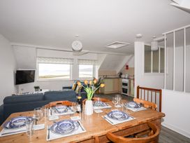A dining area with a table set for meals and kitchen furnishings at Towyn - 7 Ty'n Don