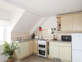 A kitchen with cabinets, stove, microwave and sink at Towyn - 7 Ty'n Don