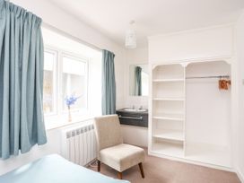A bedroom with a chair and a shelf at Towyn - 7 Ty'n Don