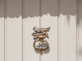 A bird-shaped door knocker on a wooden panel at The End in Langport
