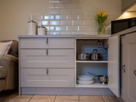A kitchen with pots and bowls in a cabinet at The End Low Ham near Langport