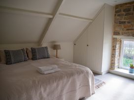 A bedroom with a bed, lamp, and window at The End Low Ham near Langport