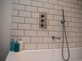 A bathroom with a tub and shower panel at The End in Low Ham near Langport