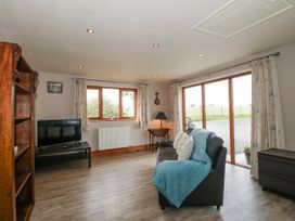 A living room with a television and sofa at Bluebell Cottage