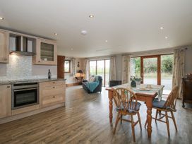 A kitchen and living area with a table and chairs at Bluebell Cottage