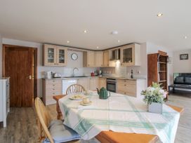 A kitchen with wooden cabinets and dining table at Bluebell Cottage