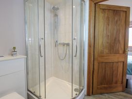 A shower with glass doors and a wooden door at Bluebell Cottage