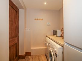 A laundry room with a washing machine and microwave at Bluebell Cottage