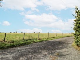 A gravel road with a fence and cattle in a field at Bluebell Cottage 