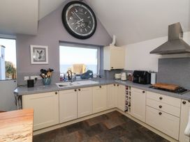 A kitchen with a clock and sink and large window at Lenny's Place in Watchet
