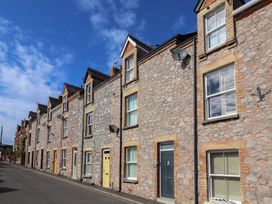 A row of stone buildings with various windows and a yellow door at Lenny's Place in Watchet