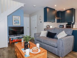 A living room with a sofa, coffee table, and television at Mayfly Lodge in St Tudy