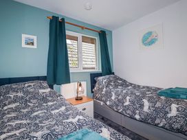 A bedroom with two single beds and a window at Mayfly Lodge St Tudy