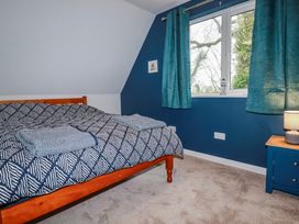 A bedroom with a bed and window at Mayfly Lodge in St Tudy