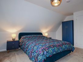 A bedroom with a bed and nightstands at Mayfly Lodge St Tudy