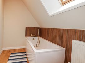 A bathroom with a bathtub and wooden wall at Mayfly Lodge St Tudy