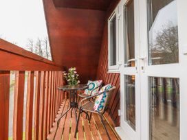 A balcony with table and chair at Mayfly Lodge in St Tudy