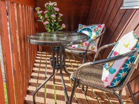 A deck with a table and two chairs at Mayfly Lodge in St Tudy