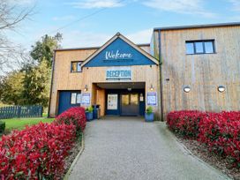 An outdoor reception area with signage and plants at Mayfly Lodge in St Tudy