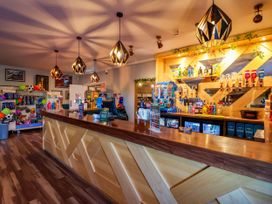A bar with a counter and shelves containing drinks at Mayfly Lodge in St Tudy