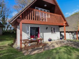 An outdoor area with a table and chairs at Mayfly Lodge in St Tudy