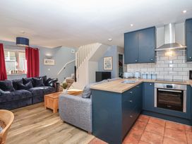 A living room with a couch and kitchen in Mayfly Lodge St Tudy