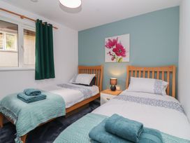 A bedroom with two beds and a nightstand at Mayfly Lodge in St Tudy