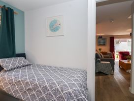 A bedroom with a bed and doorway leading to a living room at Mayfly Lodge St Tudy