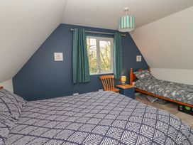 A bedroom with two beds and a chair at Mayfly Lodge in St Tudy
